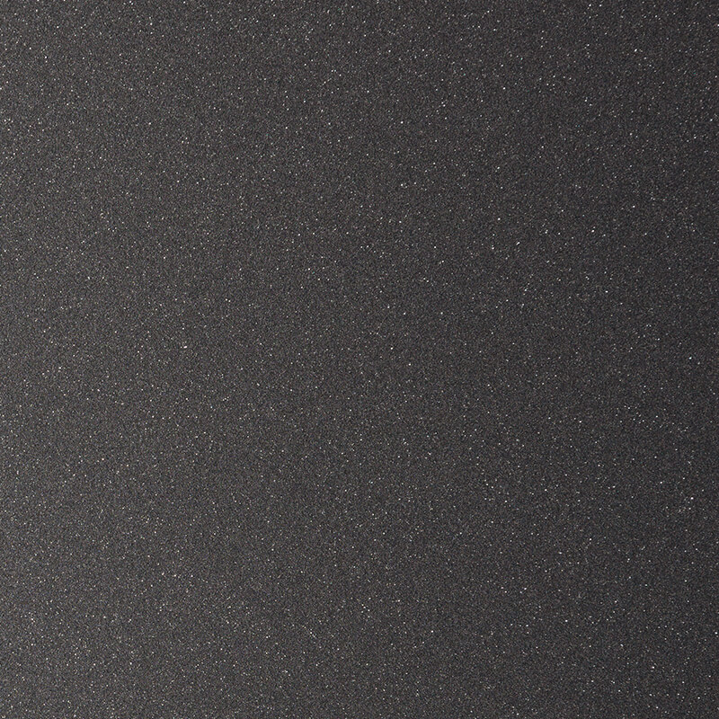 Close-up of a black, textured surface with a subtle, fine-grain, sparkly or glittery appearance, resembling sandpaper or a metallic finish.