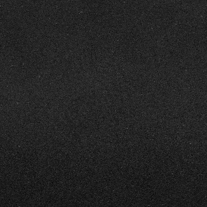 A close-up view of a dark, fine-grained textured surface, possibly black sand or asphalt, filling the entire frame evenly.