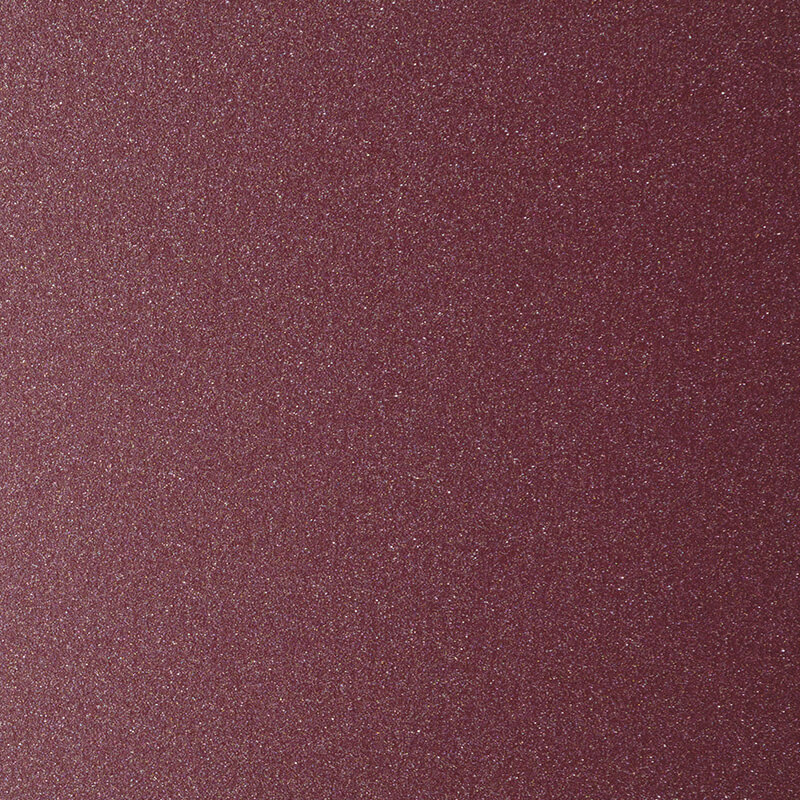 A close-up of a surface covered in fine, reddish-purple glitter or sandpaper, showing a textured and slightly sparkling appearance.
